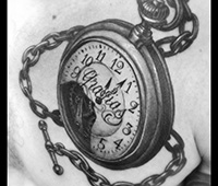 tatuaje en blanco y negro en el pecho: reloj de cadena con gracias escrito